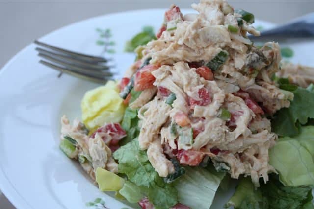 plate with fork and chicken salad topped on a bed of greens