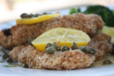 chicken piccata on a plate with lemon and capers