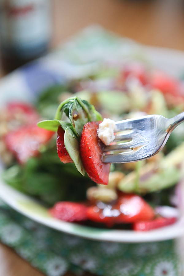 close up of fork with spinach, strawberry, and cheese covered in raspberry balsamic vinaigrette