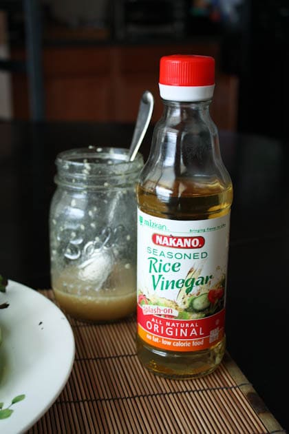 jar of asian sesame vinaigrette with a spoon and a bottle of seasoned rice vinegar
