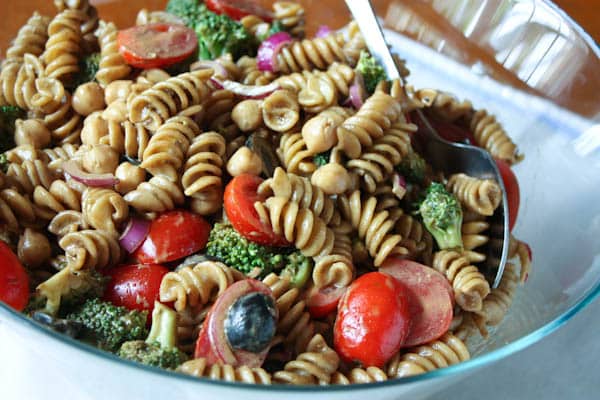 pasta salad with cherry tomatoes, olives, red onions, and broccoli in a bowl