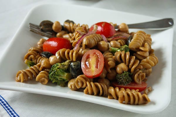 pasta salad with cherry tomatoes, olives, red onions, and broccoli on a plate with a fork