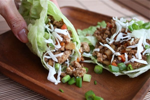 wooden plate with lettuce wraps stuffed with ground turkey, water chestnuts, and chopped green onion