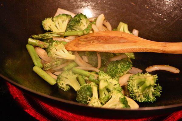 stir frying vegetables in a wok with a wooden spoon