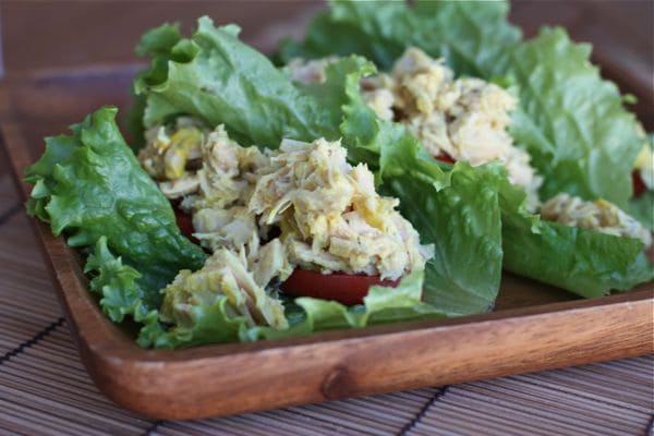 wooden plate with lettuce wrapped with tuna salad and sliced tomatoes