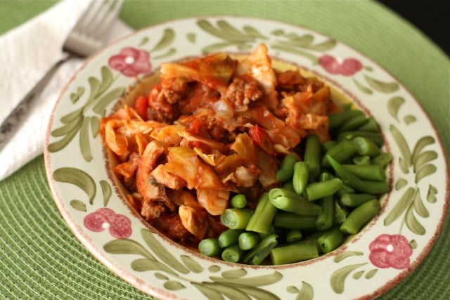 plate of cabbage with ground turkey covered in red sauce and a side of green beans