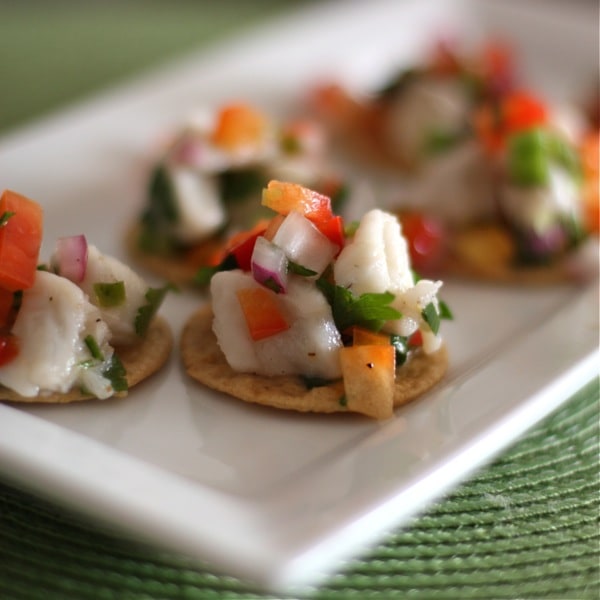 plate of 6 crackers topped with ceviche mix of diced white fish, red onions, tomatoes, and cilantro