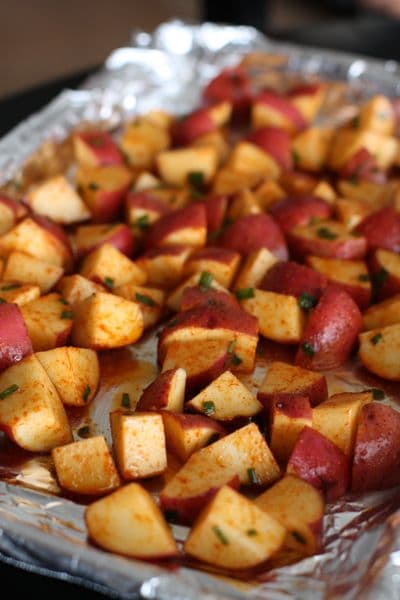 cubed uncooked red potatoes seasoned with smoked paprika on an aluminum foil lined baking sheet