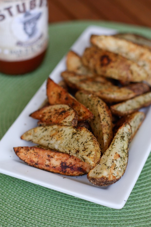 oven roasted potato wedges with dill on a white rectangle serving plate