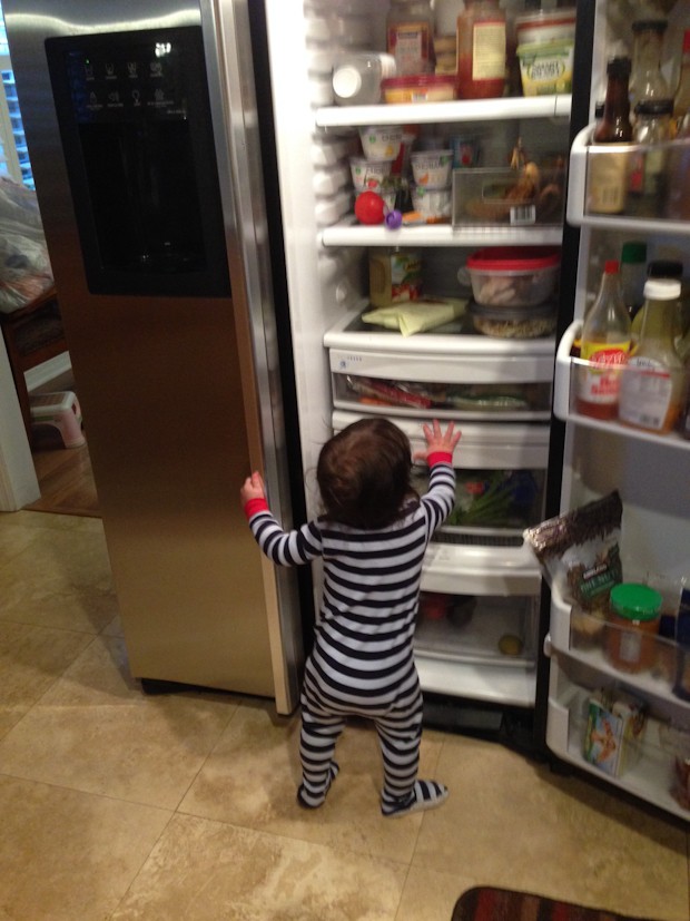 young toddler boy looking in open fridge