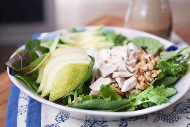 salad plate with salad greens, sliced pears, chopped rotisserie chicken and walnuts
