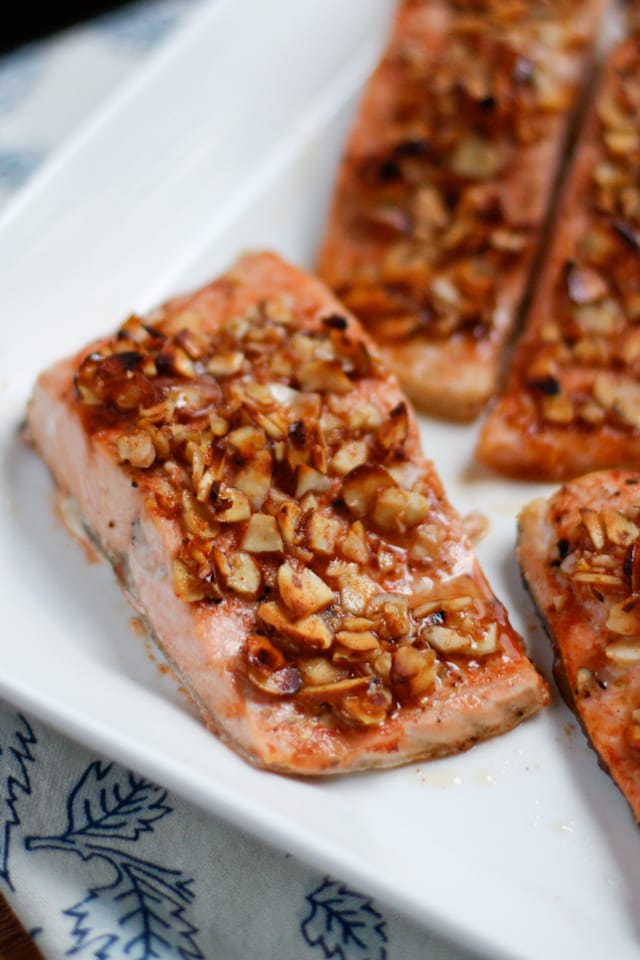 plate of salmon topped with crushed almonds with a side of greens