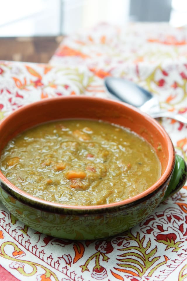 bowl of split pea soup on fall colored table napkin with spoon in background