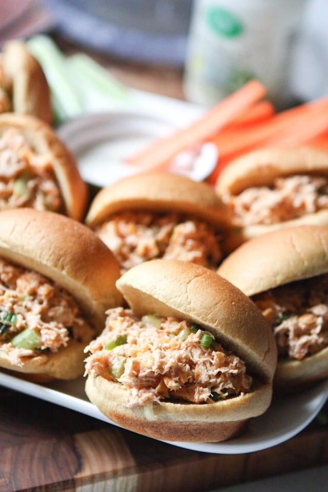 plate of chicken salad sliders in buns alongside carrot and celery sticks with a cup of ranch