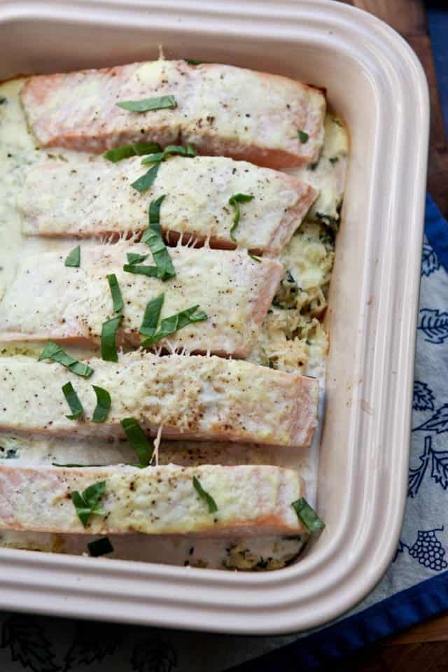 baking contained with salmon topped with a creamy sauce and green garnish
