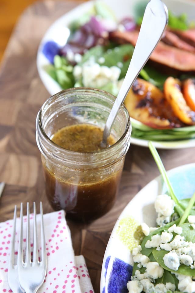 jelly jar filled with honey balsamic dressing with salad in background