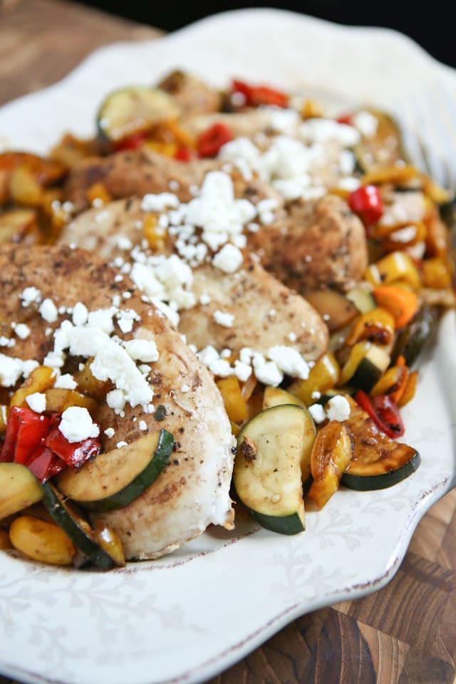 plate of chicken with peppers and zucchini covered in balsamic vinegar and topped with feta cheese