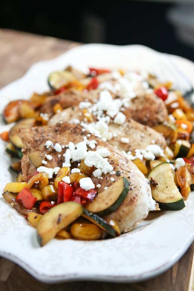 plate of chicken with zucchini, peppers, and corn topped with feta cheese