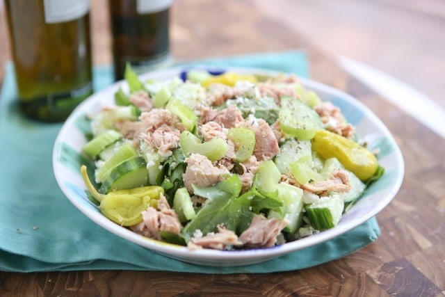 bowl of greens topped with tuna, cucumbers, celery, and peppers sprinkled with cheese