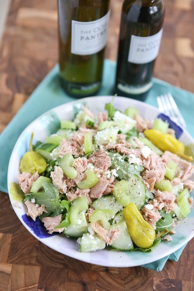 bowl of greens topped with tuna, cucumbers, celery, and peppers sprinkled with cheese