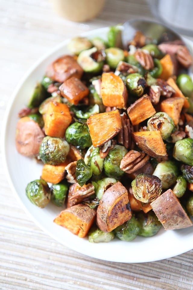 close up of roasted sweet potatoes, brussels sprouts and pecans on a white plate