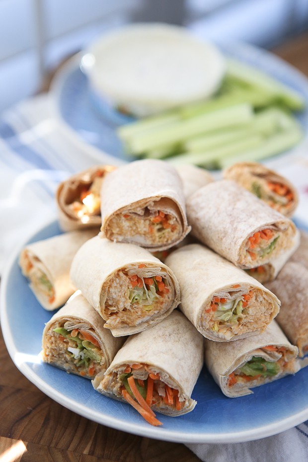 plate of wraps with various vegetables and chicken salad cut in half and stacked on each other