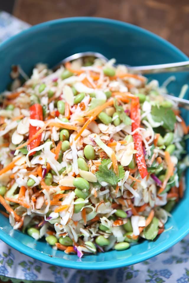 asian slaw salad of slaw mix, mathstick carrots, red bell pepper, Fisher almonds, edamame, and cilantro in a large blue bowl