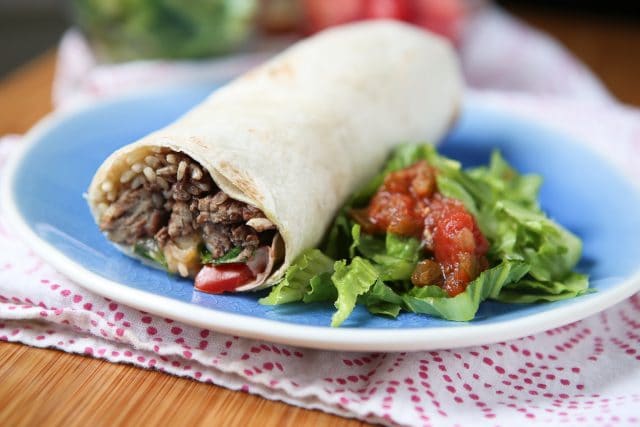 plate with a burrito stuffed with rice, black beans, and ground turkey alongside chopped romaine lettuce topped with salsa