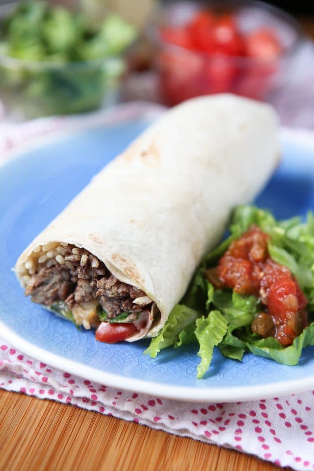 plate with a burrito stuffed with rice, black beans, and ground turkey alongside chopped romaine lettuce topped with salsa