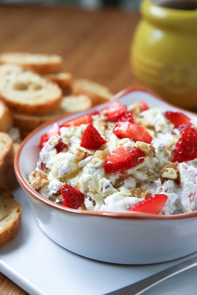 bowl filled with goat cheese spread made with strawberries, honey, basil and walnuts