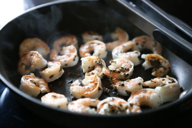 shrimp cooking in skillet with seasonings on top