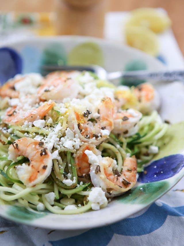 bowl of zuchinni noodles topped with shrimp and feta cheese