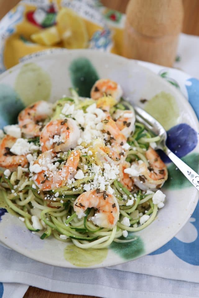 bowl of zuchinni noodles topped with shrimp and feta cheese