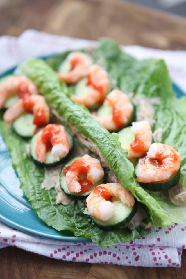 plate of 2 romaine lettuce leaves stuffed with shrimp and cucumber, drizzled with hot sauce