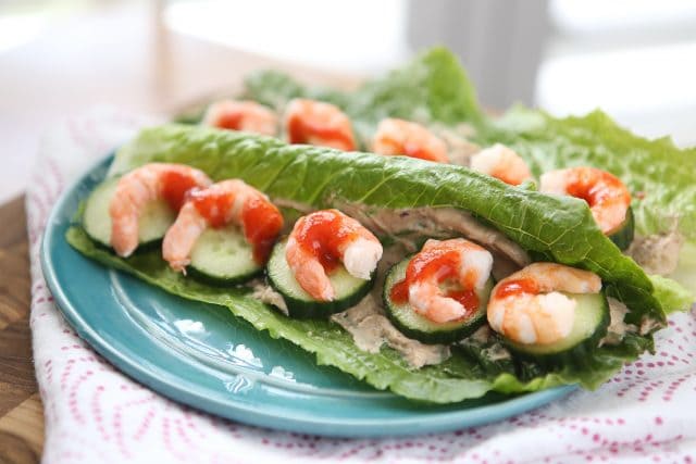 plate of 2 romaine lettuce leaves stuffed with shrimp and cucumber, drizzled with hot sauce
