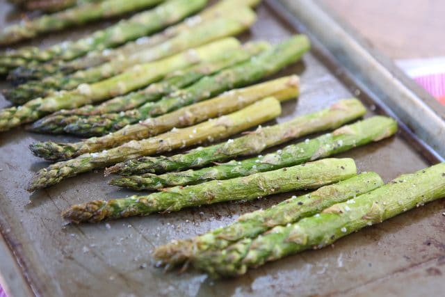 roasted asparagus on a sheet pan sprinkled with salt and pepper