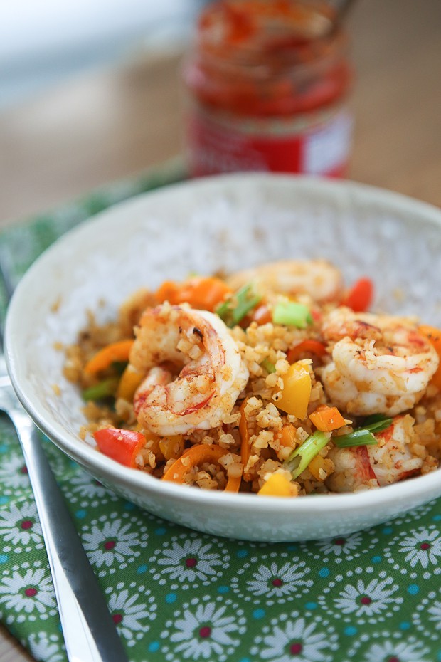 bowl of cauliflower rice with shrimp, red and yellow bell peppers, and green onions