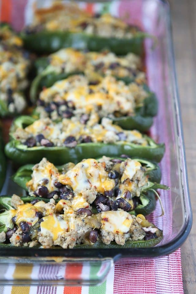 glass baking pan with poblano peppers stuffed with ground turkey, black beans, and topped with melted cheese