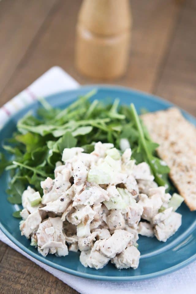 plate of chicken salad with an arugula salad and crackers on the side