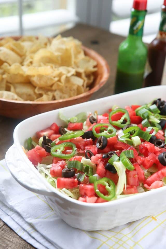 This Layered Taco Dip is full of all the ingredients that we love in our tacos, but in dip form. Great to serve while entertaining family and friends! #UndeniablyDairy #DairyGood #ad