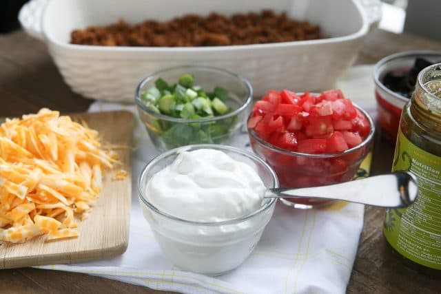 This Layered Taco Dip is full of all the ingredients that we love in our tacos, but in dip form. Great to serve while entertaining family and friends! #UndeniablyDairy #DairyGood #ad