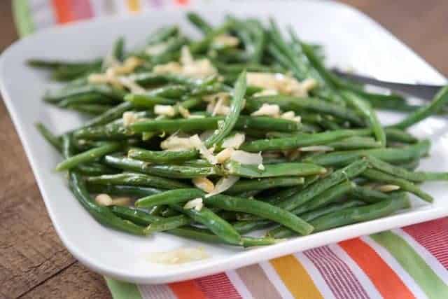 green beans with almonds on a white platter