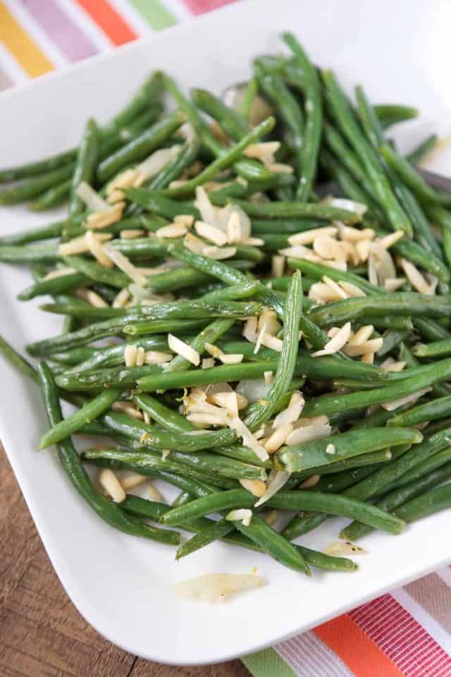 white platter with roasted green beans and almonds