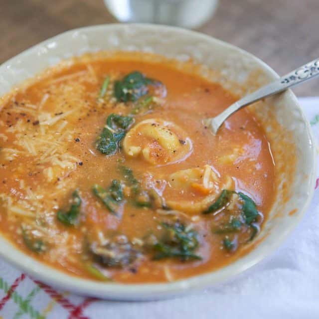 close up of bowl of tomato and spinach soup with tortellini