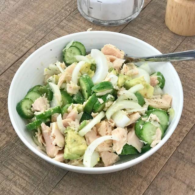 cucumber, avocado and onion salad with tuna in white bowl